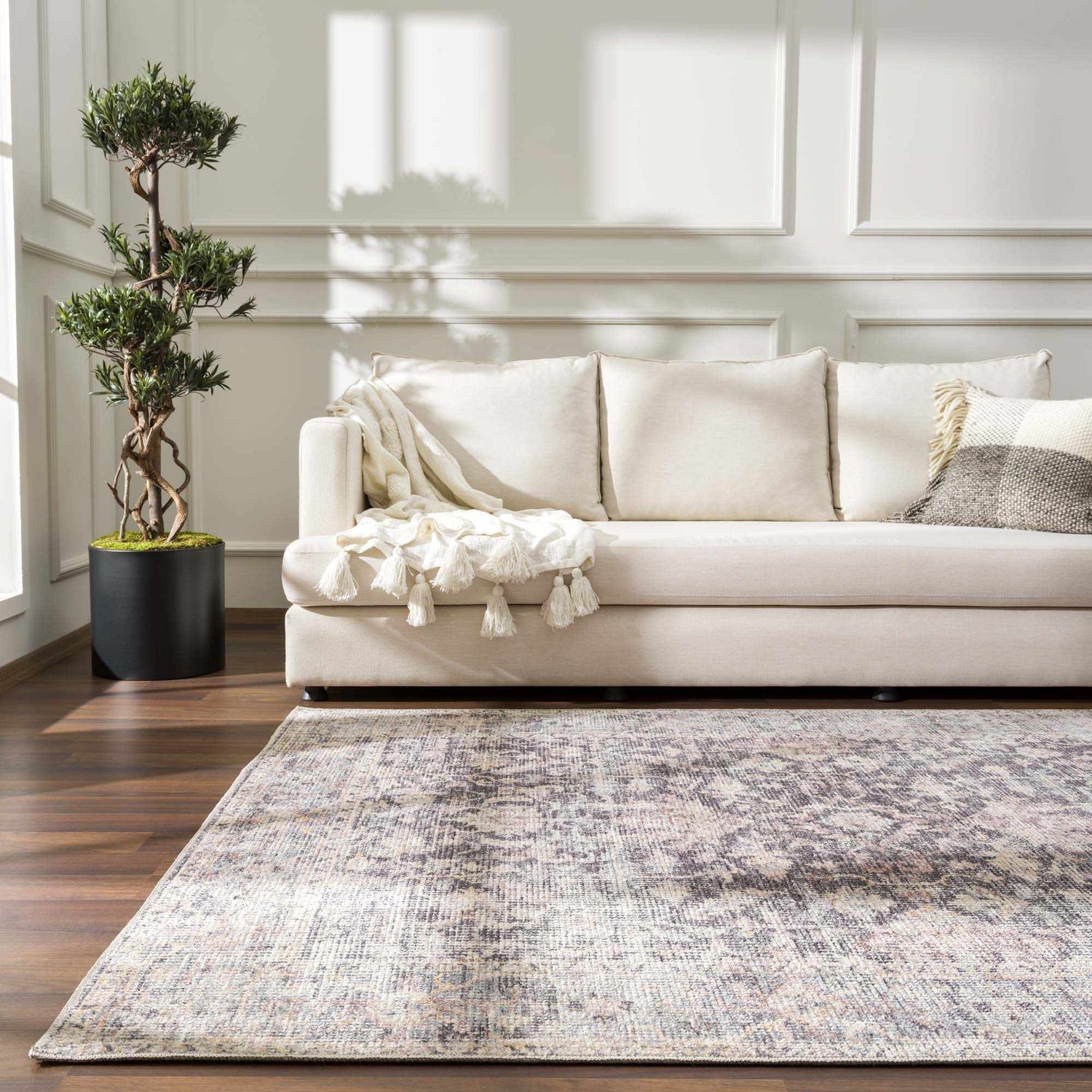 Living room scene with a neutral sofa and the vintage-style Nyota Area Rug in gray, ivory, and brown tones. Roomscene-Rectangle