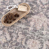 Close-up of the Nyota Area Rug showing its traditional vintage pattern and soft gray, beige, and mauve colors. Styleshot