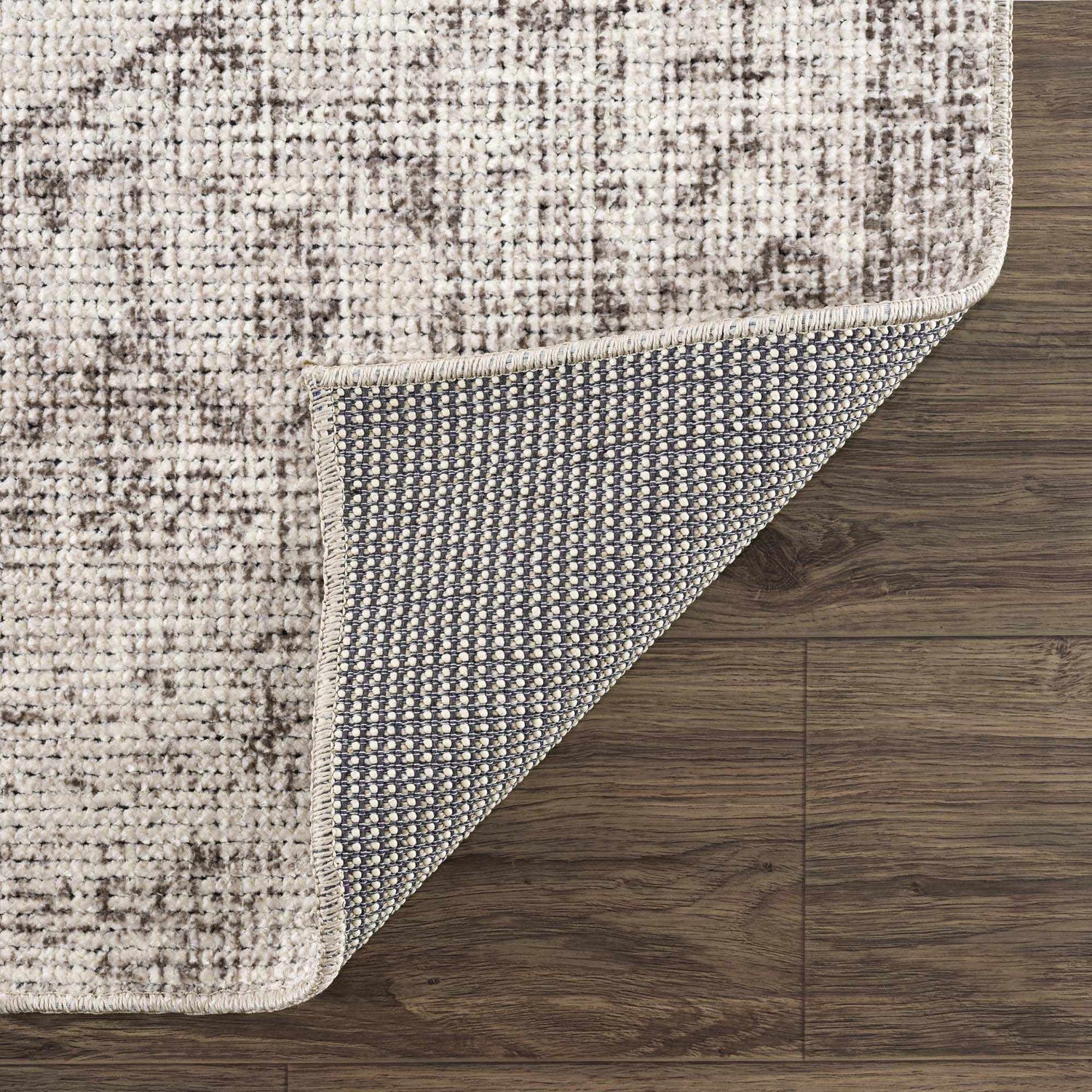 Close-up of Mortye Cream & Brown Medallion Area Rug showing texture, backing, and medallion pattern on a dark wood floor. Fold