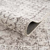Close-up of the Mortye Cream & Brown Medallion Area Rug showing its texture, backing, and vintage-style pattern. Fold