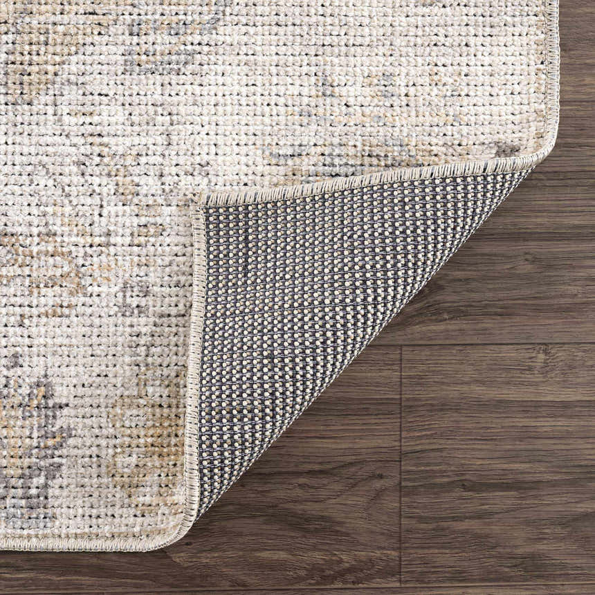 Close-up of the Melor Area Rug showing its traditional vintage pattern, texture, and backing on a wood floor. Fold