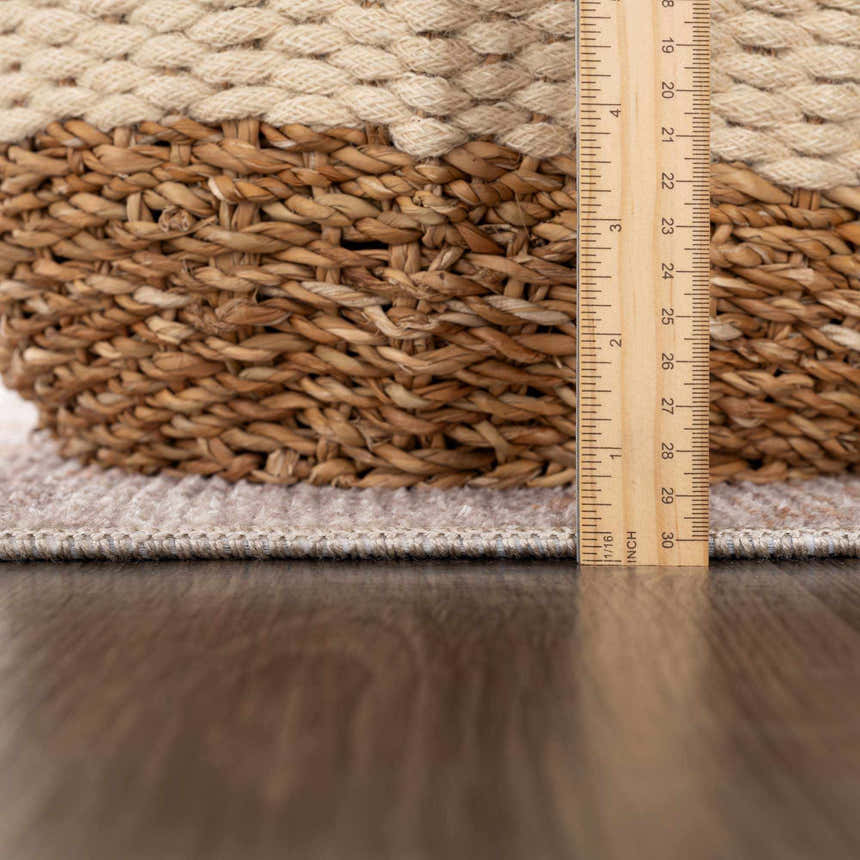Close-up of the textured edge and pile height of the Melor Area Rug, next to a ruler for scale. Pile