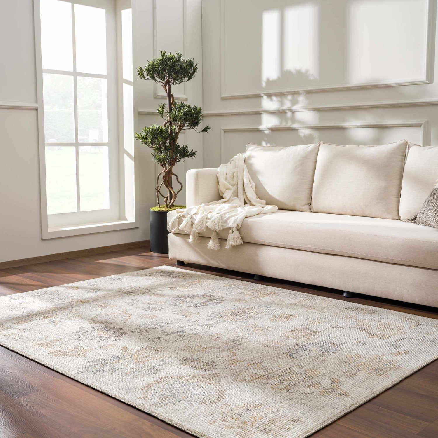Living room with a beige sofa and the vintage-style Melor Area Rug in neutral tones on a dark wood floor. Roomscene-Rectangle