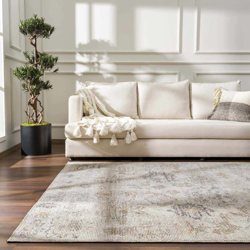 Living room scene with a cream sofa and the vintage-style Melor Area Rug in neutral tones on a dark wood floor. Roomscene-Rectangle