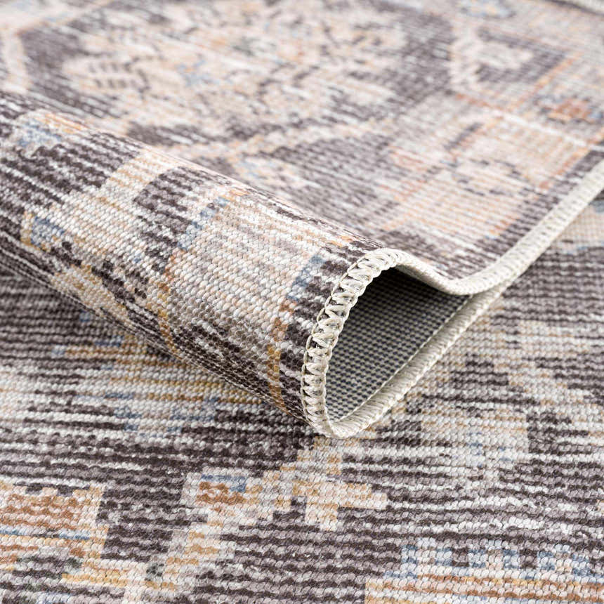 Close-up of the Okoth Area Rug showing its traditional pattern, neutral colors, and machine-woven texture. Fold