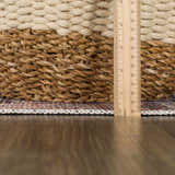 Close-up of the Okoth Area Rug showing the rug's edge, pile height, and woven texture next to a ruler and a wicker basket. Pile
