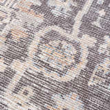 Close-up of the Okoth Area Rug showing a traditional pattern in gray, tan, and blue hues. Texture