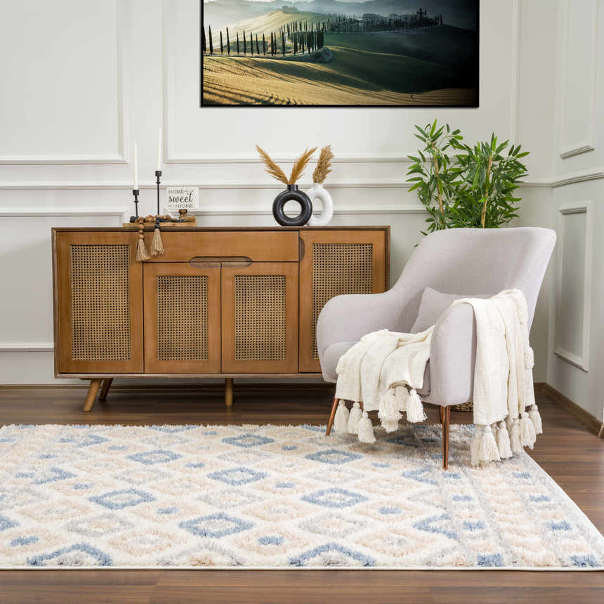 Living room scene with Eivin Pink & Blue Area Rug, wood cabinet, gray chair, and Tuscan landscape art. Roomscene-Rectangle