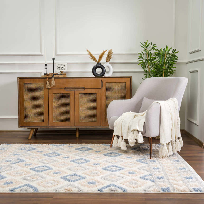 Living room scene with Eivin Pink & Blue Area Rug, light gray chair, wood cabinet, and dark wood floors. Bohemian style. Roomscene-Rectangle