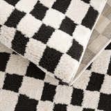Close up of the Lajos Black & White Checkered Plush Rug, showing the geometric pattern and soft, textured polyester. Fold