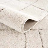 Close-up of the beige Keanu Area Rug showing its plush texture, geometric pattern, and durable backing. Fold