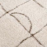 Close-up of the plush, off-white Keanu Area Rug with a brown geometric line pattern. Texture