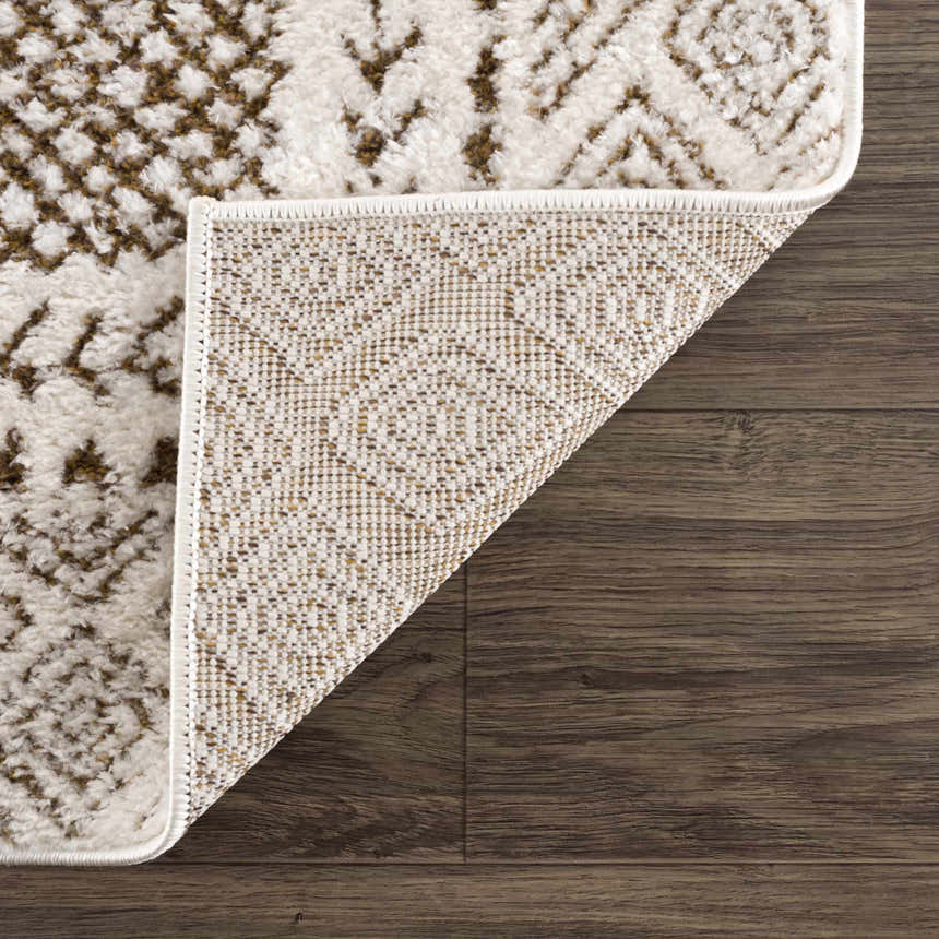 Close-up of the Julio Scandi Boho Area Rug in brown, beige, and ivory on a dark wood floor, showing the rug's backing. Fold