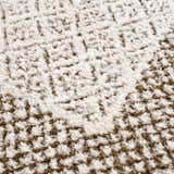 Close-up of the Julio Scandi Boho Area Rug. Features a textured, geometric pattern in beige, bone, brown, and ivory. Texture