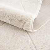Close-up of the plush, ivory Keone Area Rug, showing its soft texture, geometric pattern, and durable backing. Fold