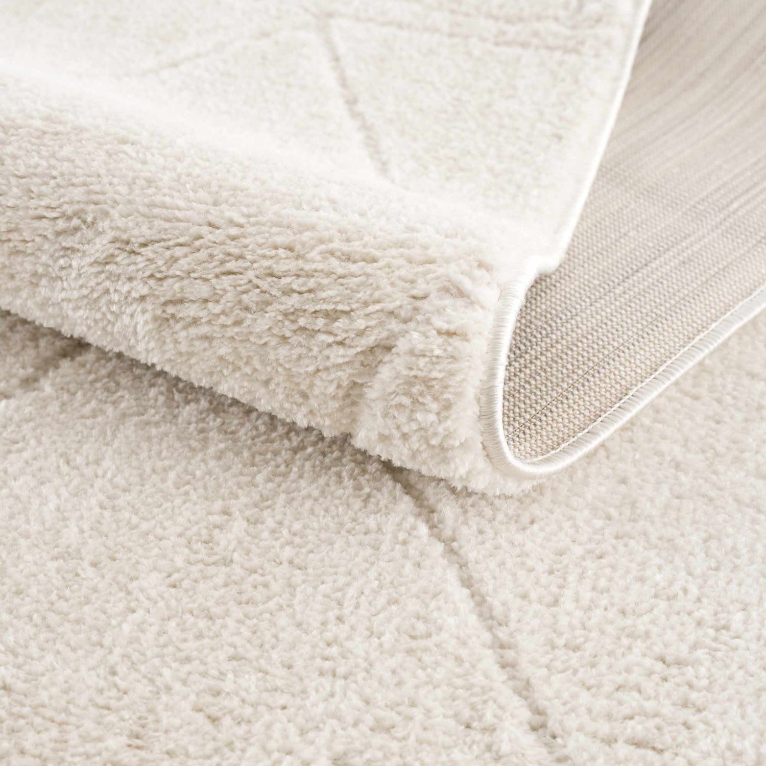 Close-up of the plush, ivory Keone Area Rug, showing its soft texture, geometric pattern, and durable backing. Fold
