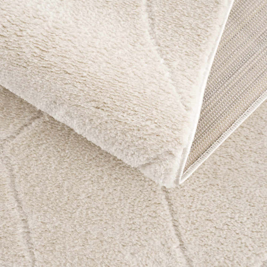 Close-up of the plush Keone Ivory Area Rug, showing its soft texture, ivory color, and machine-woven construction. Fold