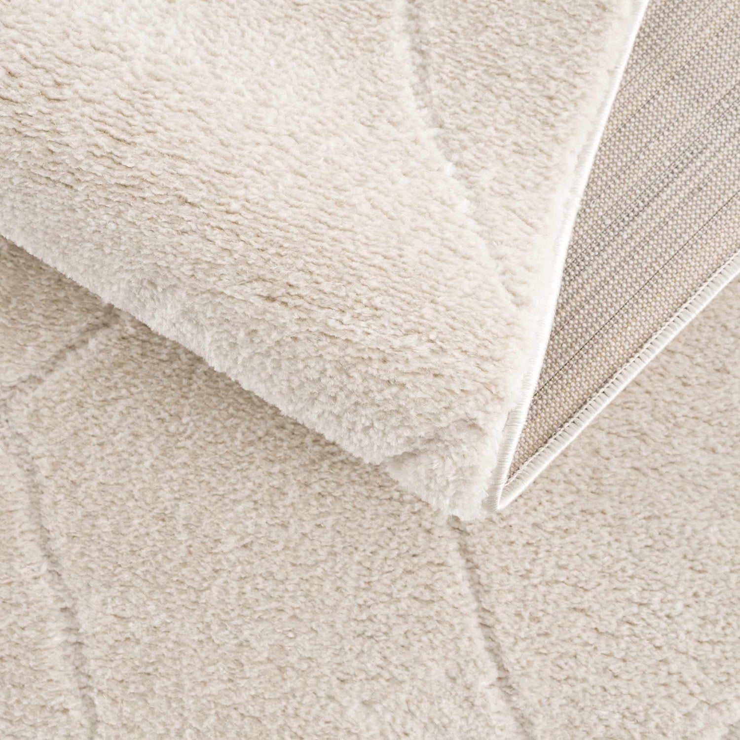 Close-up of the plush Keone Ivory Area Rug, showing its soft texture, ivory color, and machine-woven construction. Fold