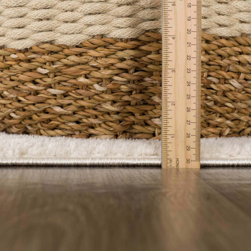Close up of the Keone Ivory Area Rug showing the beige woven texture and pile height with a ruler. Pile
