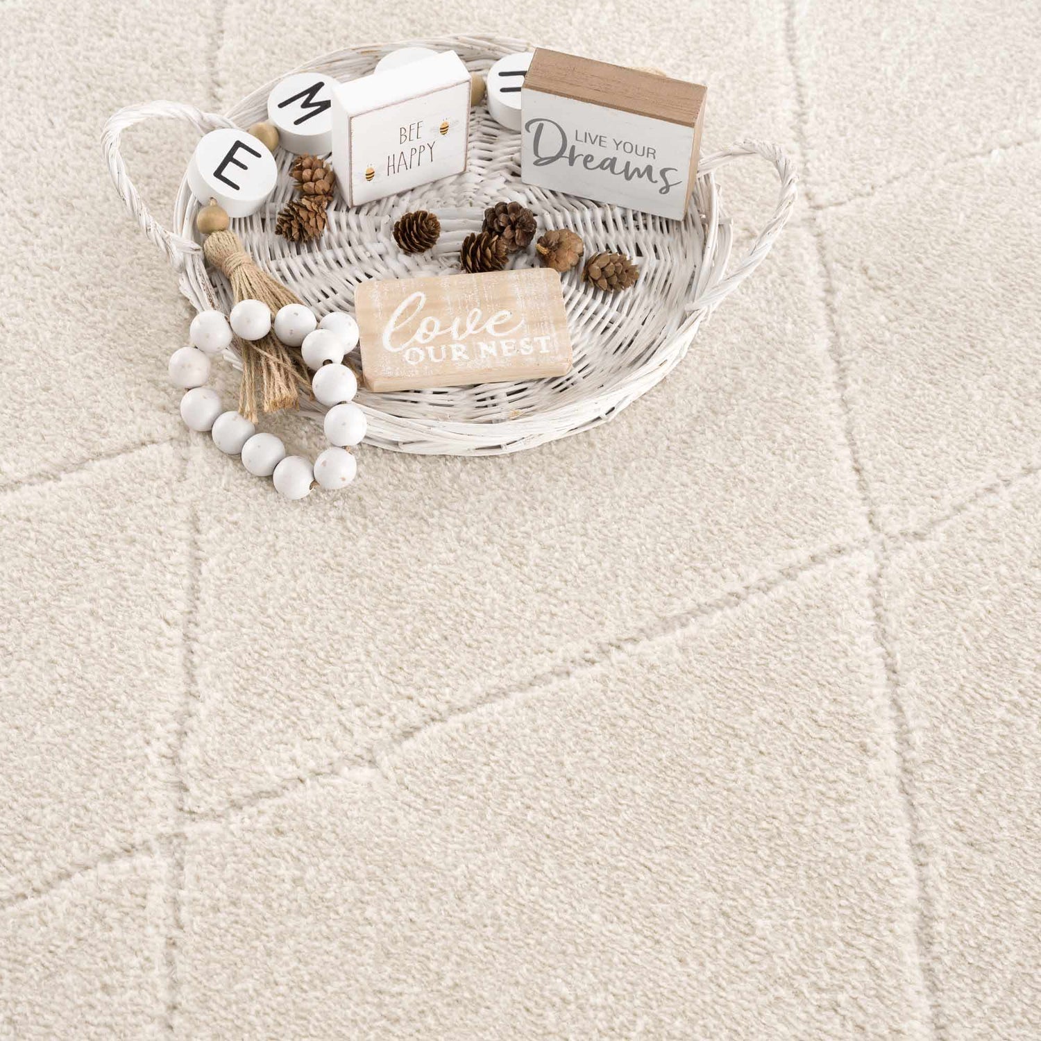 Close-up of the ivory Keone area rug showing the subtle geometric pattern and soft, textured weave. Farmhouse decor accents. Styleshot
