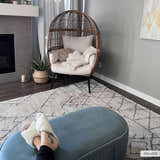 Cozy living room scene with a Flintville Moroccan Shag Area Rug, egg chair, and blue ottoman. Roomscene-Rectangle