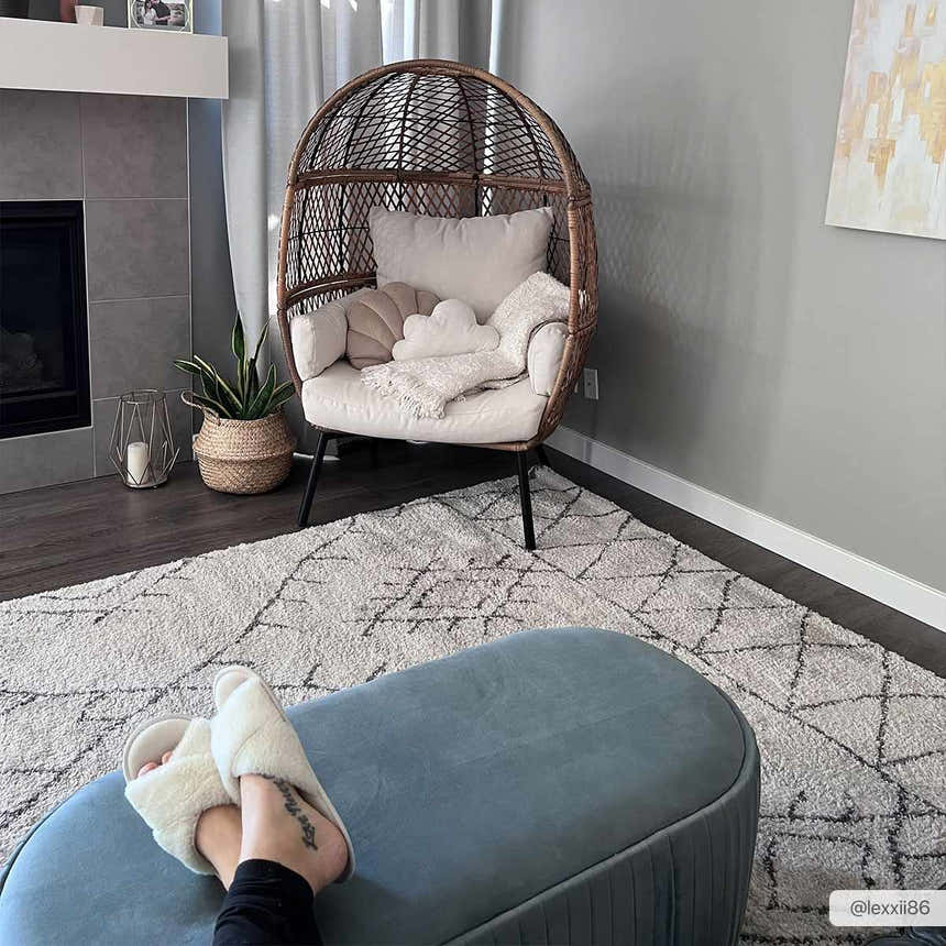 Cozy living room scene with a Flintville Moroccan Shag Area Rug, egg chair, and blue ottoman. Roomscene-Rectangle