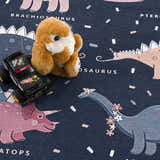 Close-up of the Milne Navy Dinosaur Washable Kids Rug featuring dinosaurs, a toy car, and a stuffed animal. Styleshot