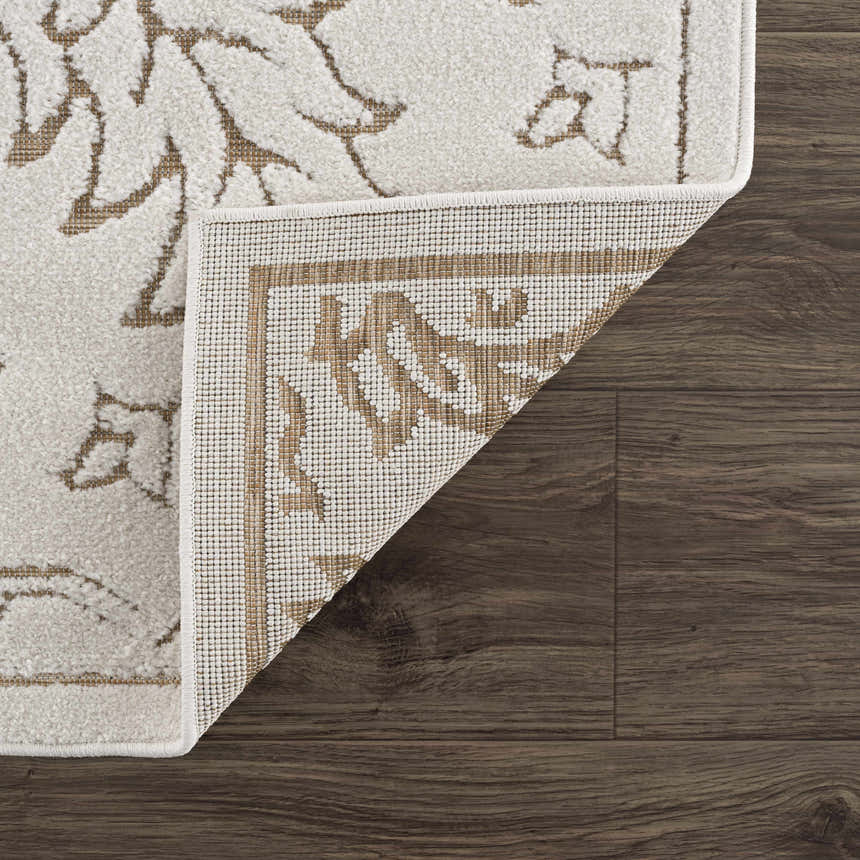 Close-up of the Tabuan 3D Outdoor Area Rug on dark wood floor. Shows floral pattern, white thatch, and rug backing. Fold