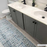 Bathroom scene with blue and cream Gandy Washable Area Rug, gray double vanity, and light wood floors. Roomscene-Runner