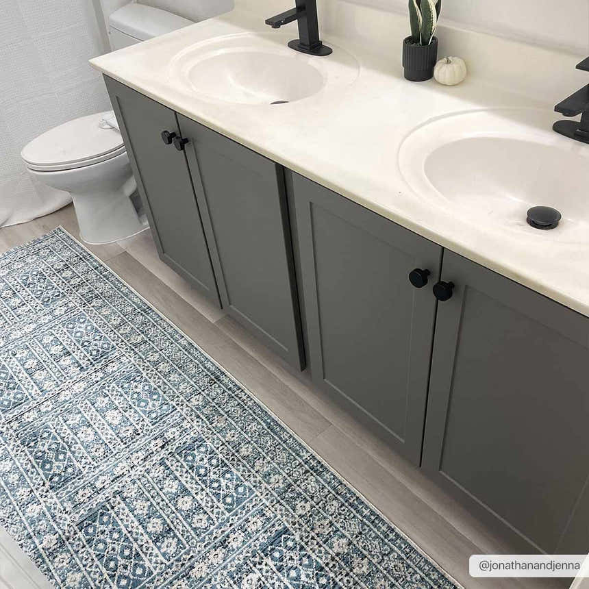 Bathroom scene with blue and cream Gandy Washable Area Rug, gray double vanity, and light wood floors. Roomscene-Runner