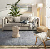 Living room scene with a gray sofa, jute pouf, and Bywong Area Rug in beige and off-white. Farmhouse style. Roomscene-Rectangle