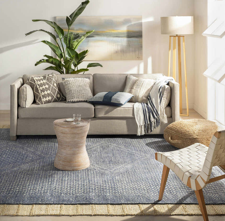 Living room scene with a gray sofa, jute pouf, and Bywong Area Rug in beige and off-white. Farmhouse style. Roomscene-Rectangle