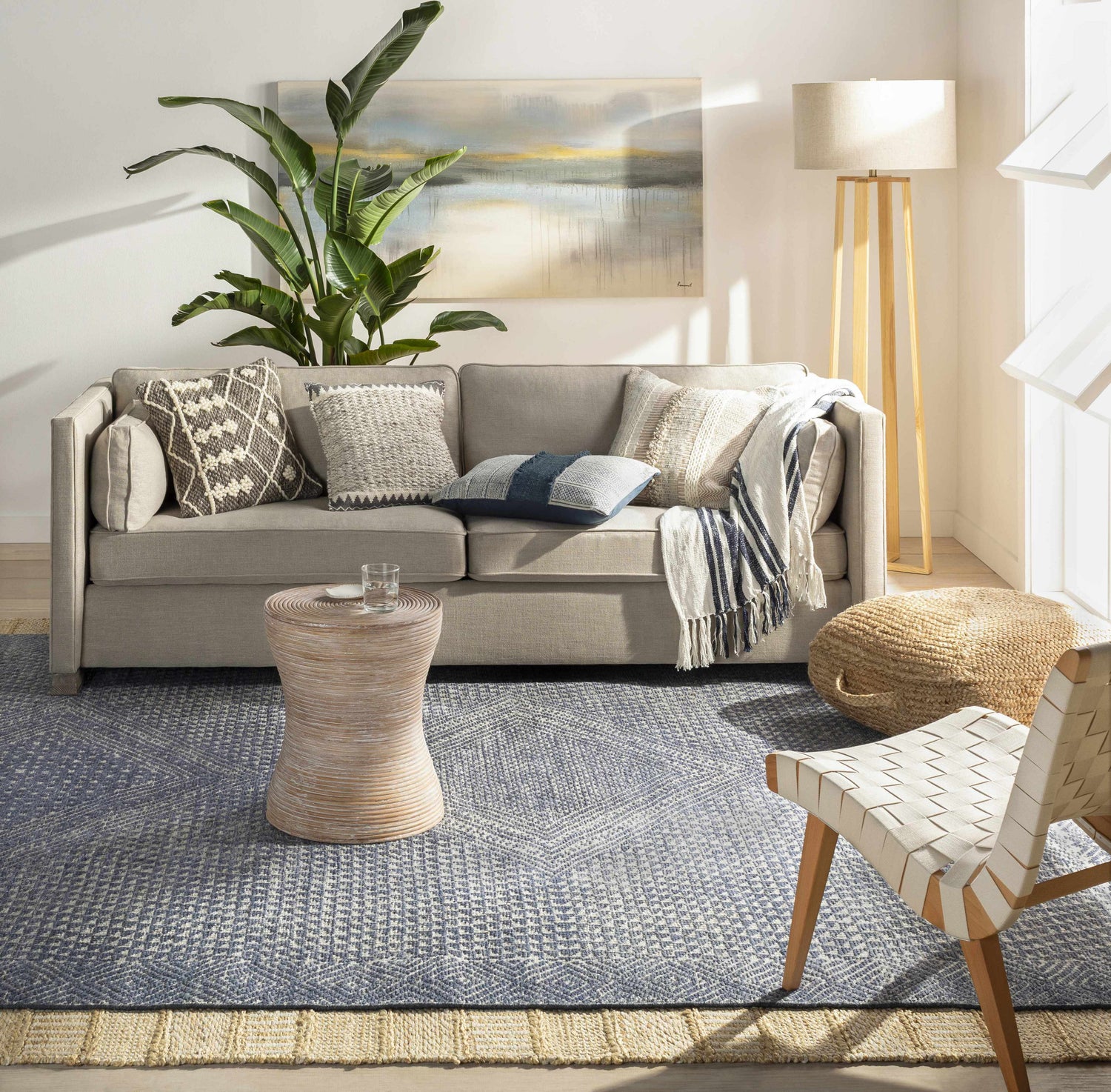 Living room scene with a gray sofa, jute pouf, and Bywong Area Rug in beige and off-white. Farmhouse style. Roomscene-Rectangle