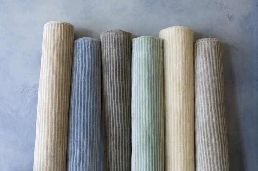 Rolled Angie Area Rugs in charcoal, blue, green, and beige. Striped, hand-loomed viscose rugs. Styleshot