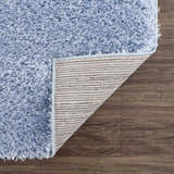 Close-up of the Faina Solid Aqua Shag Washable Area Rug showing its soft, plush texture and durable backing on a wood floor. Fold