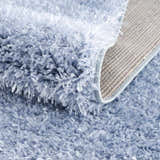 Close-up of the plush texture and backing of the Faina Solid Aqua Shag Washable Area Rug. Fold