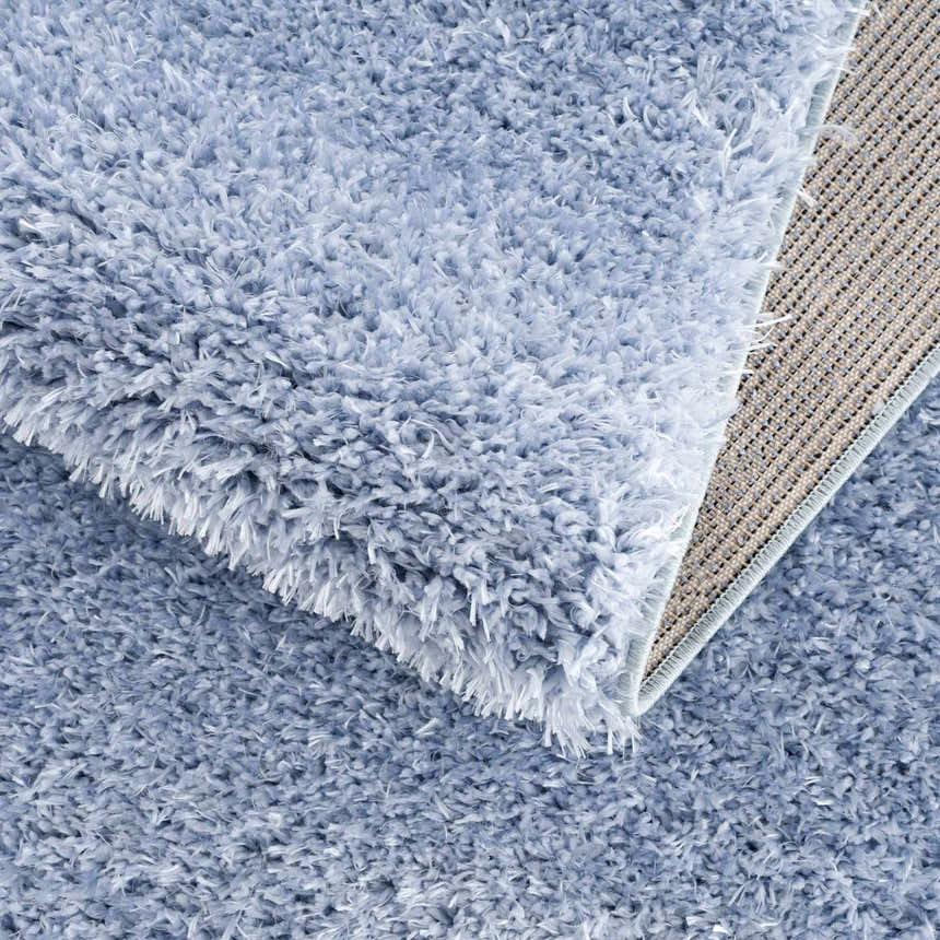 Close-up of the Faina Solid Aqua Shag Washable Area Rug showing its plush texture and backing detail. Fold