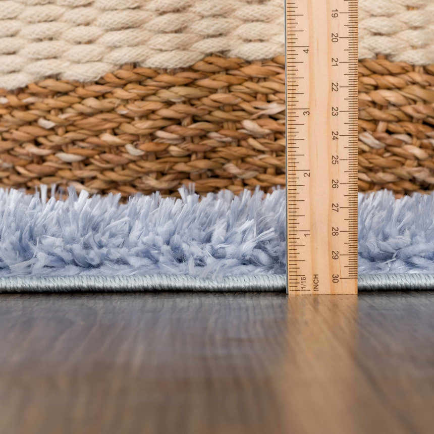 Close-up of the Faina Solid Aqua Shag Washable Area Rug showing its plush texture and color, with a ruler for scale. Pile