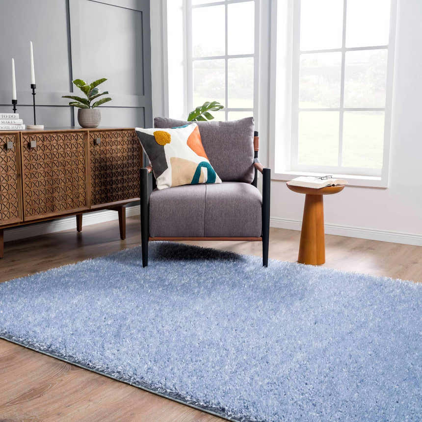 Living room scene with Faina Solid Aqua Shag Rug, gray chair, wood cabinet, and light wood floors. Bright, airy feel. Roomscene-Rectangle