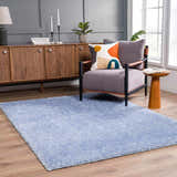 Living room scene with a Faina Solid Aqua Shag rug, gray chair, wood cabinet, and light wood floors. Roomscene-Rectangle