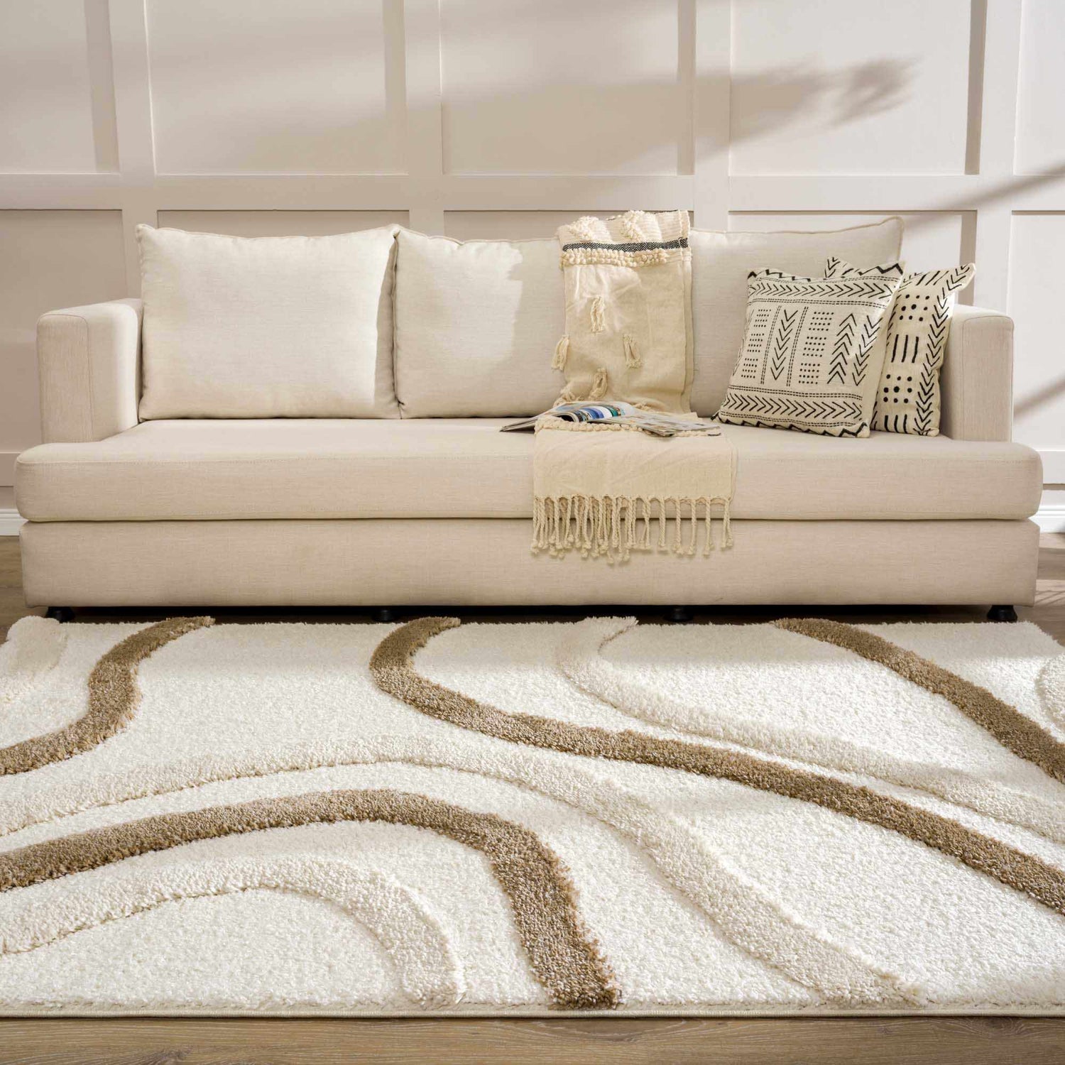 Living room scene with a cream sofa and the Espiye Area Rug in driftwood and white with a wavy pattern. Roomscene-Rectangle
