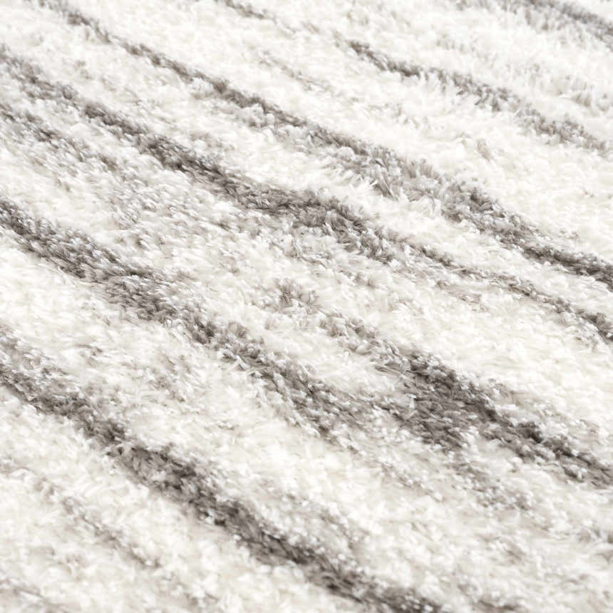 Close-up of the Lotta Area Rug. White shag rug with a subtle gray striped pattern. Soft, plush texture. Texture