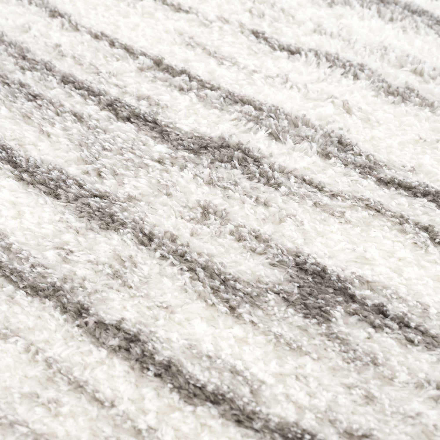 Close-up of the Lotta Area Rug. White shag rug with a subtle gray striped pattern. Soft, plush texture. Texture