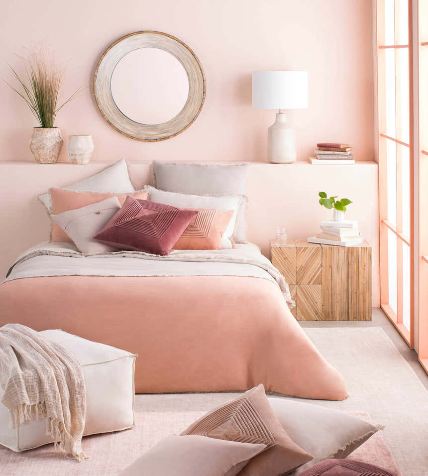 Dusty pink bedroom scene with Millinocket Area Rug, bed, side table, mirror, and soft, contemporary decor. Styleshot