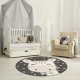 Kids nursery with white crib and chair featuring Giraffe Bowtie Animal Print Nursery Area Rug in bone, gray, and nutmeg. Roomscene-Round