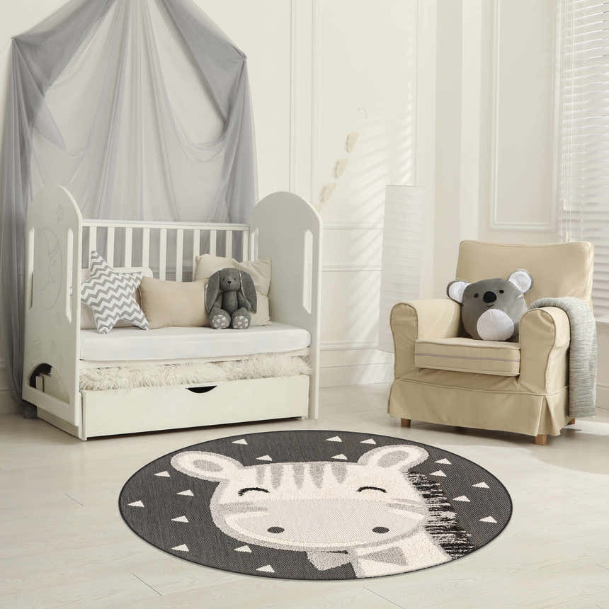 Kids nursery with white crib and chair featuring Giraffe Bowtie Animal Print Nursery Area Rug in bone, gray, and nutmeg. Roomscene-Round