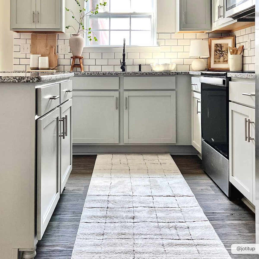 Light and airy kitchen with a beige Keanu area rug runner, gray cabinets, and white subway tile. Roomscene-Runner