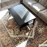 Living room scene with a Kokstad Area Rug in arctic stone, beige, brown, and blue under a black coffee table and gray sofa. Roomscene-Rectangle