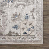 Close up of the Bakir Area Rug, showcasing its blue and gray traditional pattern and soft texture on a wood floor. Swatch