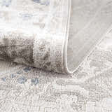 Close-up of the Bakir Area Rug showing its plush texture, gray and blue traditional pattern, and machine-woven construction. Fold